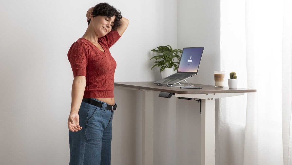 Mujer estirando su cuello mientras trabaja con el ordenador desde su casa (Foto. Freepik)