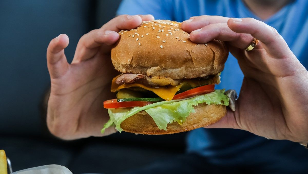 Hombre sujetando una hamburguesa (Foto. Freepik)